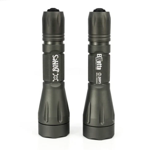 Two Bones flashlights on white background, standing on end next to each other.
