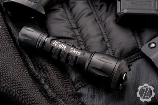 Bravo Configurator main image of Bravo flashlight on black material with various gear around it.