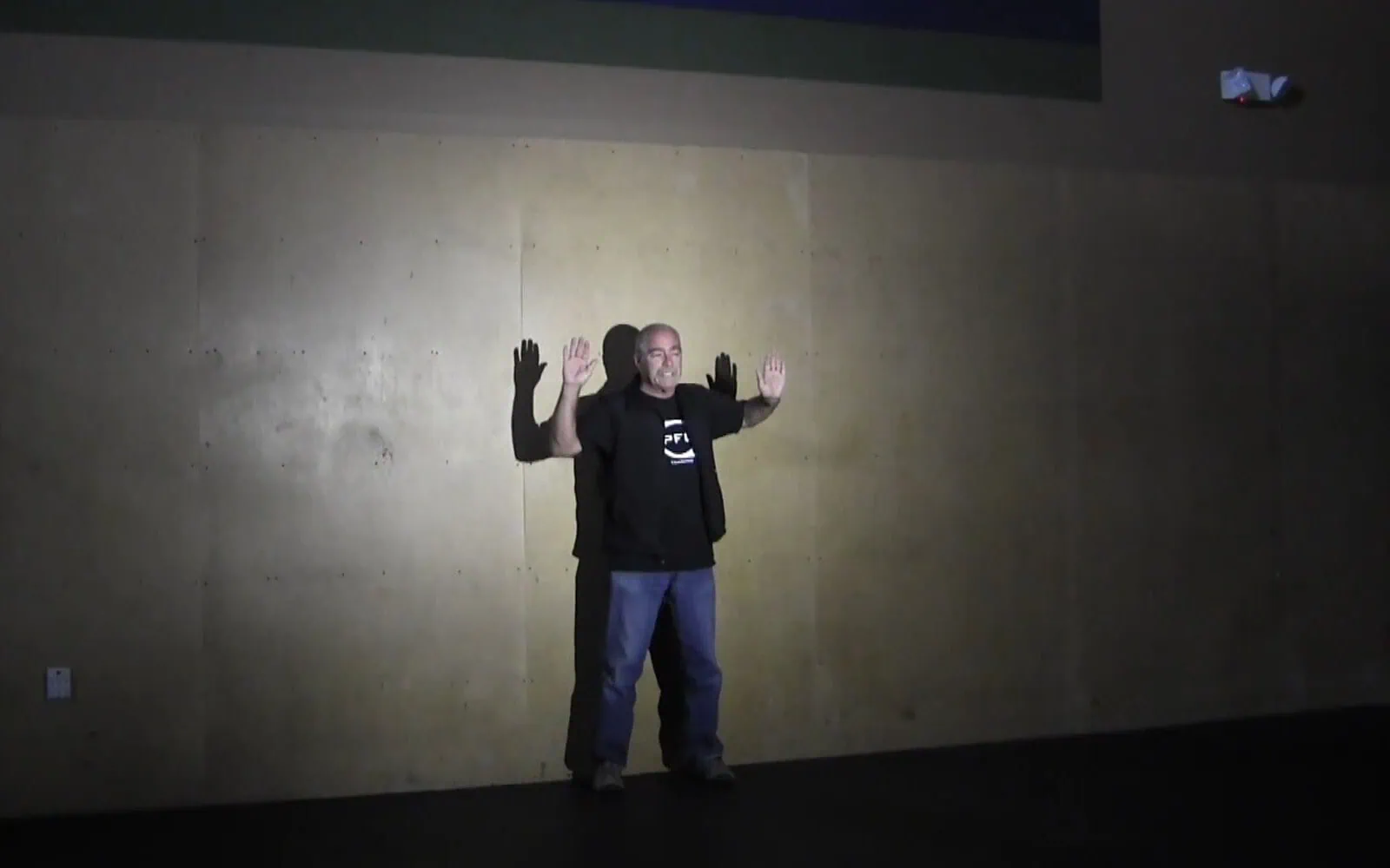 picture of man standing against a wall illuminated by the wide beam of elzetta flood lens
