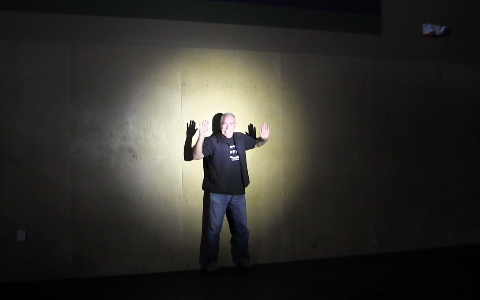 picture of man standing against a wall with hands up, illuminated by the narrow beam of elzetta standard lens