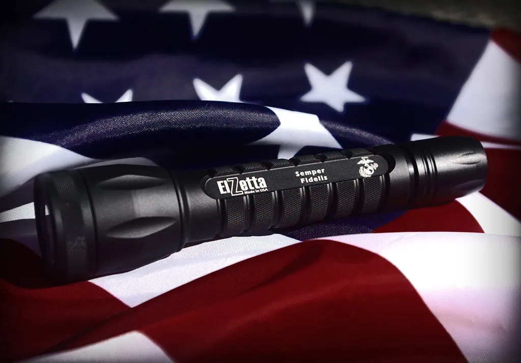 closeup photo of a C133 Charlie flashlight with usmc logo laying on an american flag