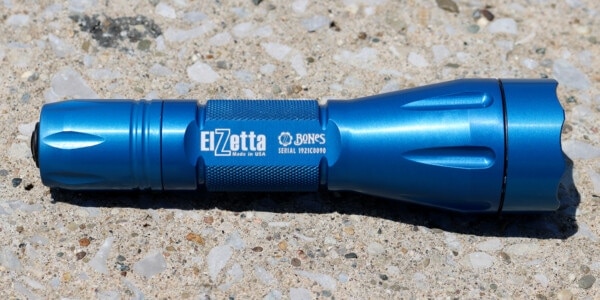 Blue Bones flashlight on concrete in sunlight.